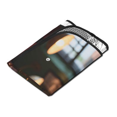 A car windshield covered by a bright yellow sun shade featuring a cartoon coffee cup spilling onto the glass